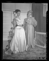 Actress Cathy Downs modeling evening gowns with unidentified woman, circa 1946