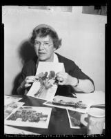 Anthropologist Margaret Mead displaying photographs of African people during visit to Los Angeles, Calif., 1954