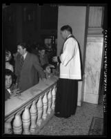 Father Paul Stroup giving sacrament on Ash Wednesday at St. Vibiana's Cathedral in Los Angeles, Calif., 1948