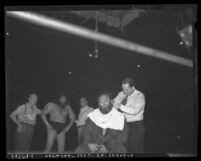 Wrestler Bluebeard Lewis getting a shave as opponent Daniel Boone Savage and others watch, 1937