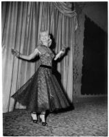 Woman models a black lace dress and gloves during a fashion show, Los Angeles