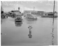 Automobiles drive through flooding at McKinley Ave. and Manchester Ave., Los Angeles, February 25, 1940