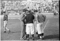 College football coach Buck Shaw confers with referees during a game, October 24, 1937