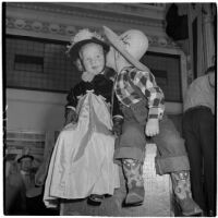 Four-year-old Jimmy Alley kissing three-year-old Margot Dutton on the cheek while they are both in costume for Anaheim's annual Halloween festival, Anaheim, October 31, 1946