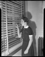 Cult victim Delight Jewett peering through blinds in U.S. Attorney Fleet Palmer's office, Los Angeles, 1937