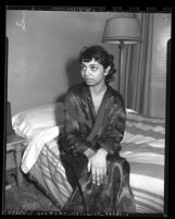 Assault victim Nydia Brisson seated on bed in boardinghouse at 259 E. 41st Place in Los Angeles, Calif., circa 1950