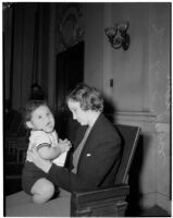 Miss Leo C. Moore sitting on a bench holding her young child, Los Angeles