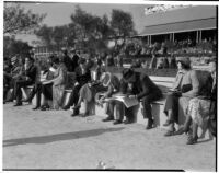 Spectators read the paper at the Santa Anita racetrack, February 22, 1937