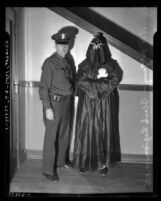 Los Angeles Police officer R. F. McGarry standing with person in Black Legion hood and robes, circa 1936