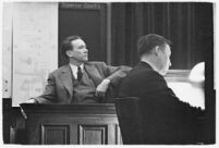 Murder suspect Robert S. James sitting on the witness stand with a plan of his house behind him, Los Angeles, 1936