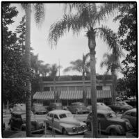 Street with a small commercial building and cars parked diagonally along both sides, California