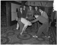 USC Kappa Alpha members spank another member with a wooden paddle inside their fraternity house, Los Angeles, 1940