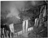 Firefighters walk through the ruins of a fire that occurred at Dura Steel Products Co., Los Angeles, 1940