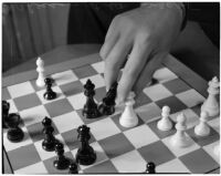 Close-up of a chess board and a player's hand checking the black king, Los Angeles