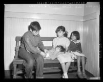 Four destitute Mexican American children sitting on bench Los Angeles, Calif., circa 1953