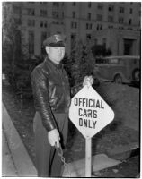 Deputy Sheriff George R. Burns standing next to a sign that says "Official Cars Only," Los Angeles