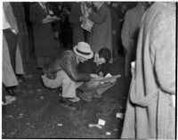 Two men reading the race listings on a rainy Derby Day at Santa Anita Park, Arcadia, February 22, 1940