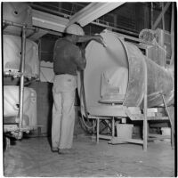 Employee sprays a new ceramic sink with a hose at the Universal Vitreous China Factory, Mentone, circa 1948