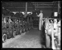 Men at work amid a line of car engines at the Los Angeles Studebaker assembly plant in Vernon, CA. Circa January 2, 1936