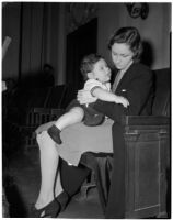 Miss Leo C. Moore sitting on a bench holding her young child, Los Angeles