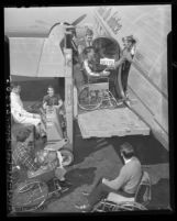 Wheel-chair basketball player Jack Heller being hoisted aboard Los Angeles Air Service plane, 1948