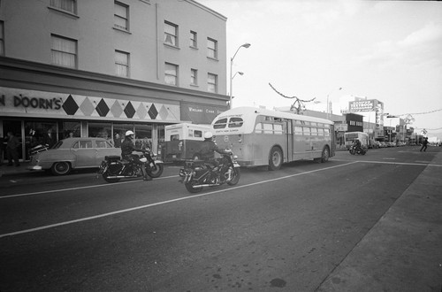 Sherriff's bus followed by motorcycle policemen leaving Sproul Hall after arrests