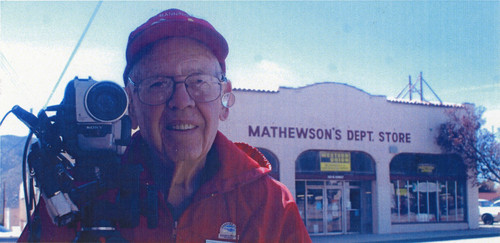 Amos ""Bud"" Mathewson with his video camera in front of Mathewson's Department Store in Banning, California