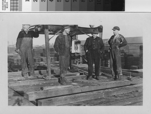 [Four men posing on platform at mill]