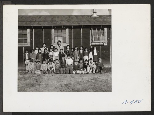 Low fifth grade pupils and their teacher, Mrs. Rhoda McGarva, outside the barracks school room. Photographer: Stewart, Francis Newell, California
