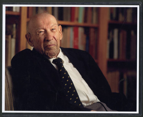 Color photograph of Peter Drucker sitting in front of a bookcase