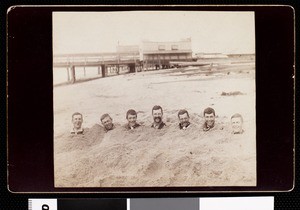 Professor and students of USC buried in sand at a beach, 1889