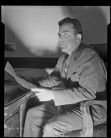 Mose E. Howard reading document at desk, Los Angeles, 1935