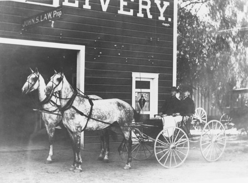 Horse-drawn buggy and passengers outside Orange Livery, 136 S. Olive St., Orange, California, ca. 1907