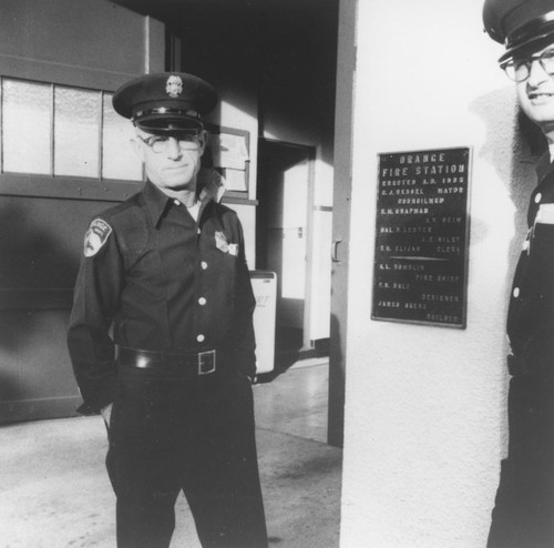 Manley Powell and Herbert Johnson next to Orange Fire Station dedication plaque, Orange, California, 1950