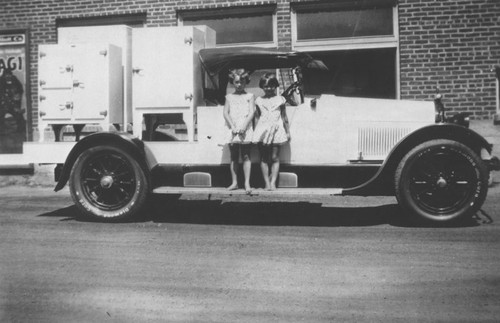 Orange Ice & Cold Storage Company delivery truck transporting ice boxes, with two little girls (Marjorie and Norma Short) standing on running board, Orange, California, ca. 1928