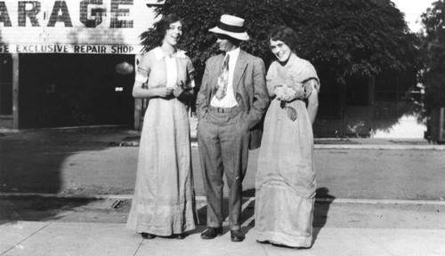 John Harms and two young ladies standing near Lush Garage, Orange, California, ca. 1915