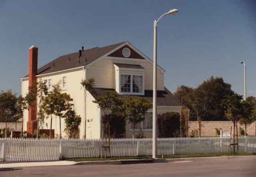 2-story yellow house behind picket fence