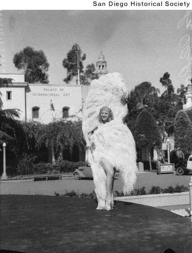 Sally Rand with feather fans standing outside the Palace of International Art during the 1936 Exposition