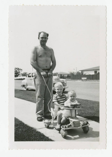 Sidney Poteet pushing children in front of family home, Los Nietos, California