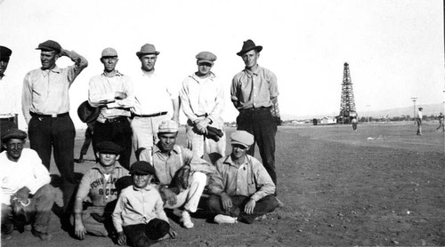 Baseball players and the audience at a game in the oilfields