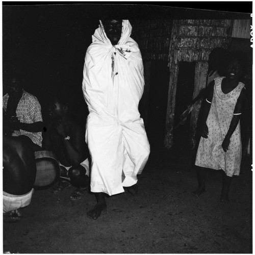 Male musicians, person in white cloth, and spectators