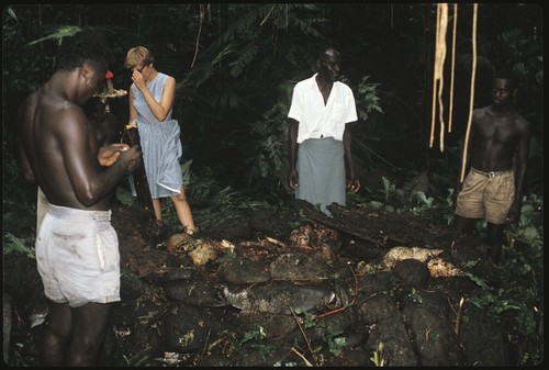 Three men and Anne Scheffler standing around a shrine