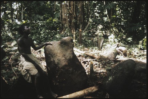 Man standing beside petroglyph at a shrine