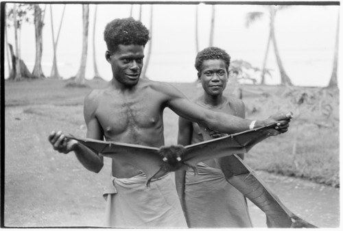 Two men holding out captured bats