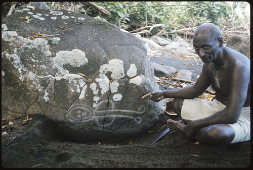 Man pointing at rock drawing