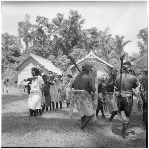 Men playing kiu, and women dancing