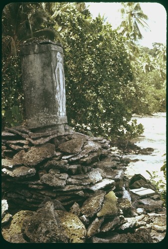 Dolo or burial urn chisled from a single block of limestone and set upon a pyramid of coral slab