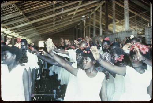 Group in a building, with white dress, red flowers in hair