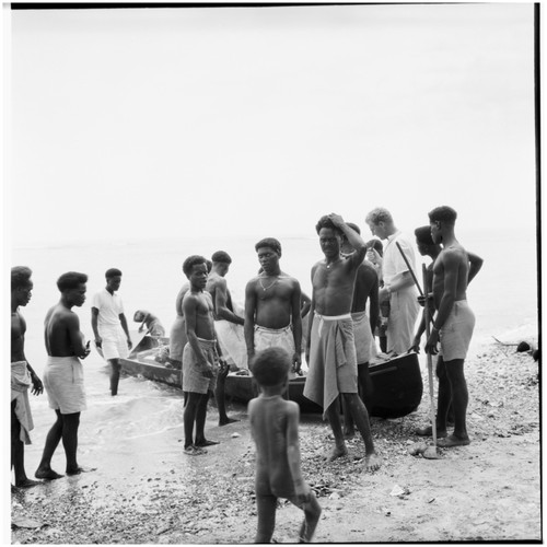 Father Laughman, men, boys, and canoe on shore