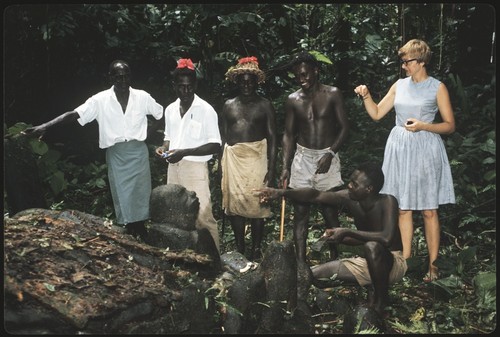 Five men and Anne Scheffler in front of shrine and carving